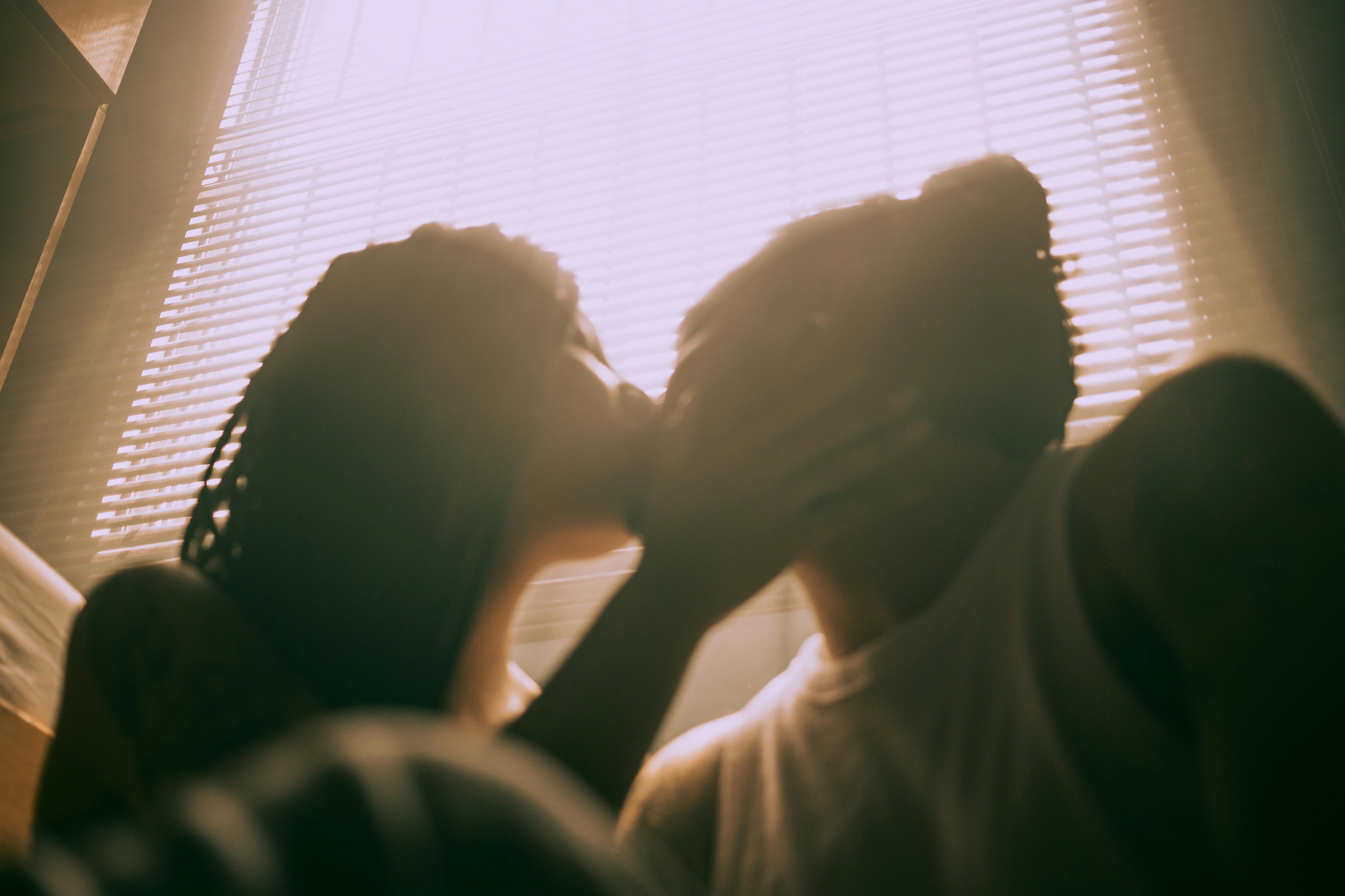 Couple kissing in warm golden light filtered through window blinds